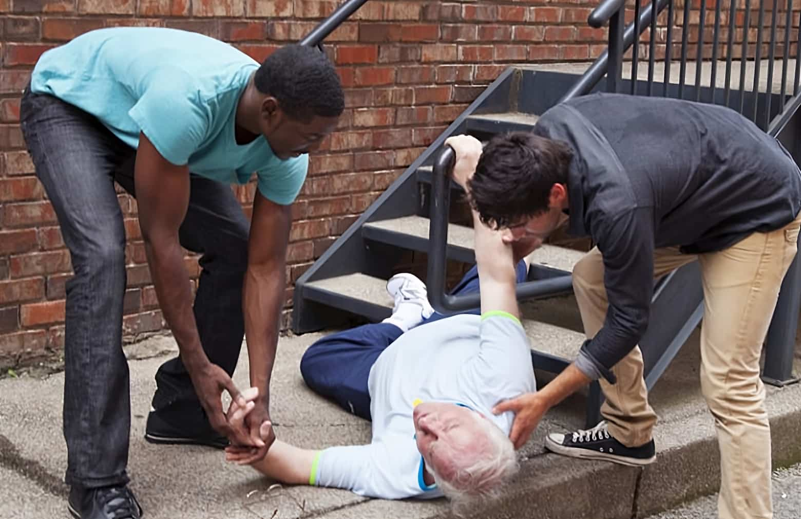 image of two people helping up a elderly person from the ground