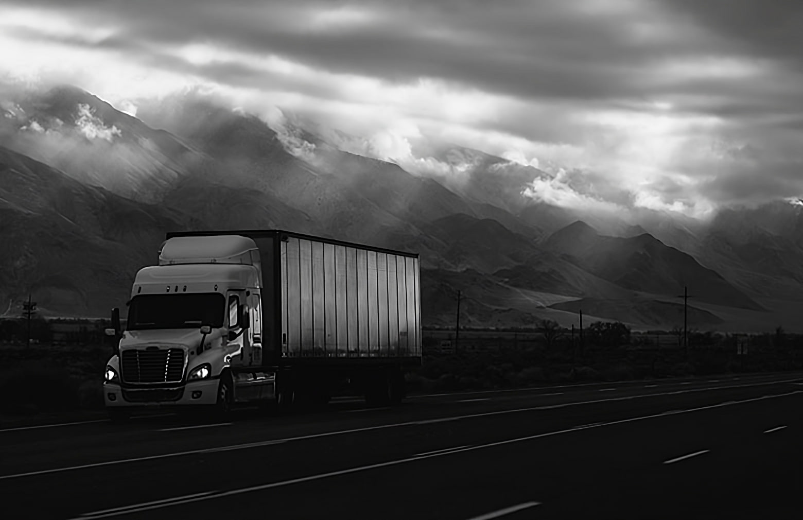 image of black and white image of a truck driving down the highway